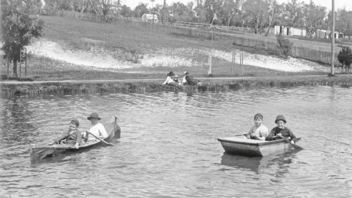 Black and white photo of children in canoes in a lake